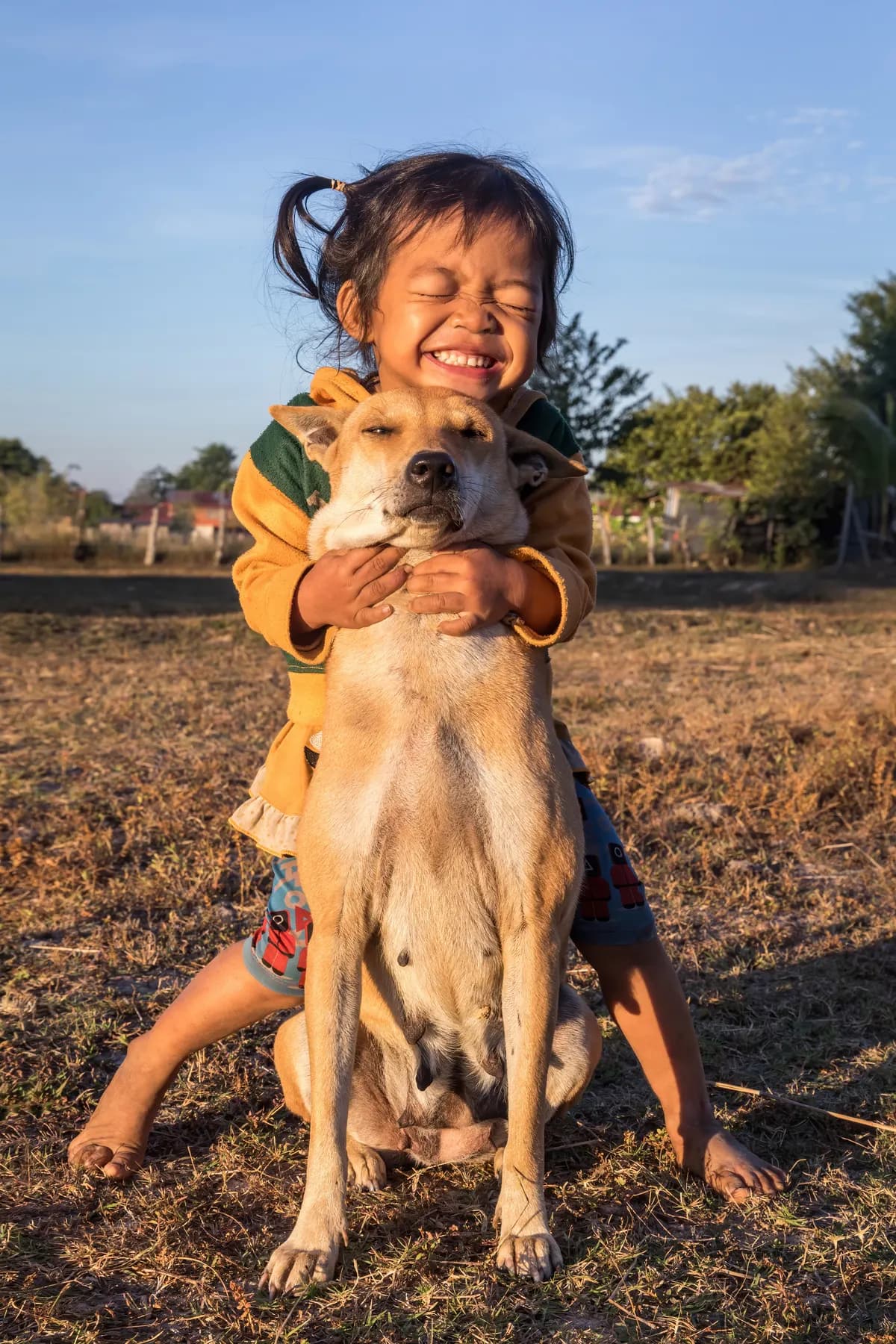 Una nena abraza a su perro al atardecer